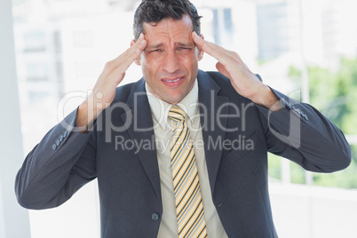 Businessman rubbing his temples and frowning at camera