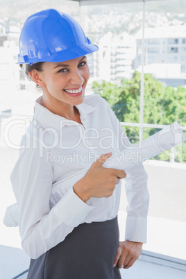 Smiling architect holding plans and wearing hardhat