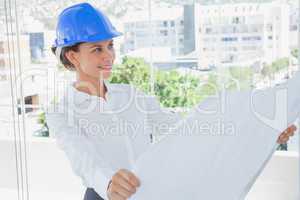 Smiling architect rolling out a blueprint