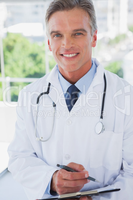 Smiling doctor standing with a clipboard