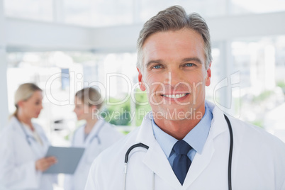 Smiling grey haired doctor standing in his office