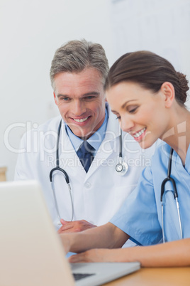 Two cheerful doctors working on a laptop