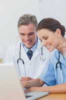 Two cheerful doctors working on a laptop