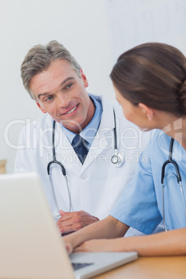 Two smiling doctors working on a laptop