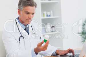 Serious doctor holding a bottle of pills