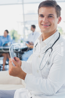 Doctor looking at the camera and using tablet pc