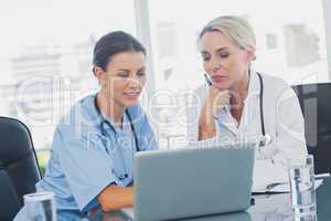 Two women doctors working on a laptop