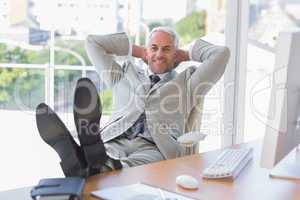 Businessman relaxing at desk and smiling at camera