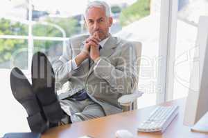 Thoughtful businessman sitting with feet up