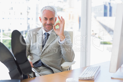 Happy businessman giving ok sign with feet up