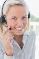 Businesswoman touching headset and smiling at camera