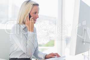 Young businesswoman working on computer on the phone