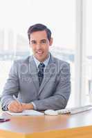 Happy businessman writing at his desk