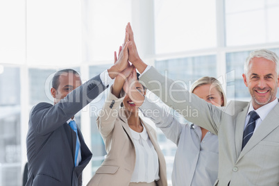 Business team high fiving and smiling at camera