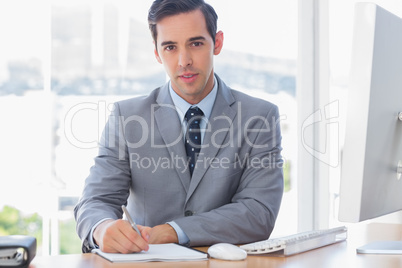 Cheerful businessman writing at his desk