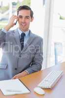 Smiling businessman on the phone looking at camera