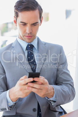 Serious businessman texting on phone