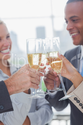Business team celebrating with champagne and clinking glasses