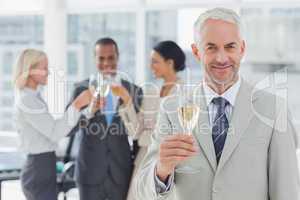 Businessman smiling at camera holding champagne