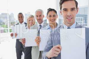 Business team in a line holding blank pages