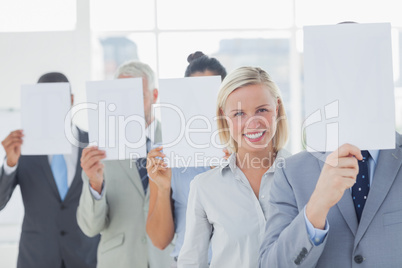 Business team covering face with white paper except for one woma