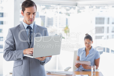 Businessman using laptop standing in office