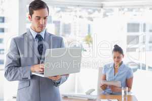 Businessman using laptop standing in office