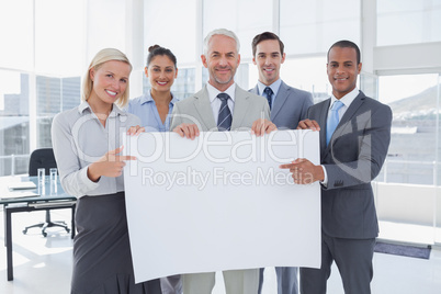 Business team holding large blank poster and pointing to it