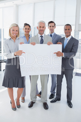 Business team holding large blank poster and smiling at camera