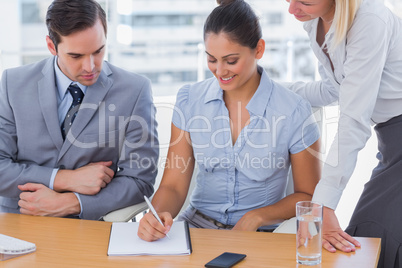 Businesswoman showing colleagues something on notepad