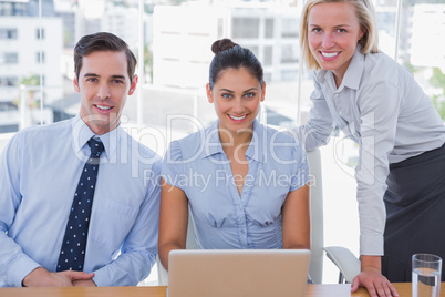 Business team with laptop smiling at camera