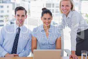Business team with laptop smiling at camera