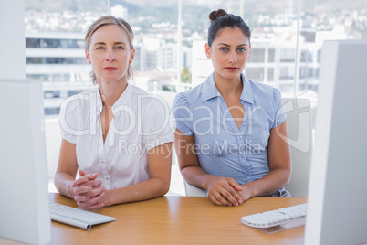 Serious businesswomen sitting side by side