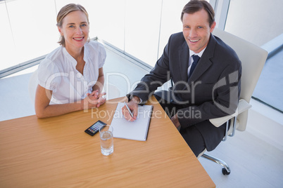 Overhead of smiling business people taking notes