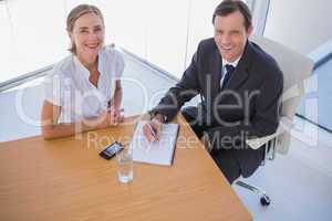 Overhead of smiling business people taking notes