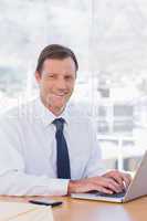 Smiling businessman working with his laptop