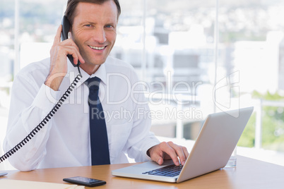 Smiling businessman posing while he is on the phone