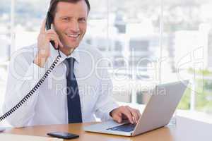 Smiling businessman posing while he is on the phone