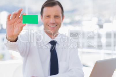 Smiling businessman holding a green business card