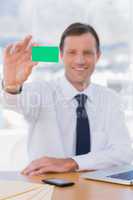 Cheerful businessman holding a green business card