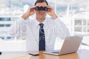 Businessman using binoculars in his office