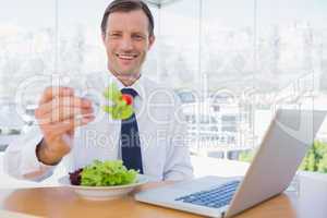 Smiling businessman eating a salad