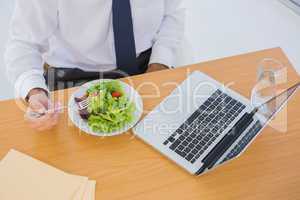 Overhead of a businessman eating a salad on his desk