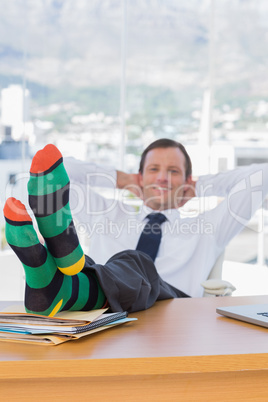 Happy businessman relaxing with feet on his desk