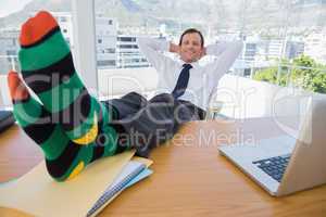 Smiling businessman having a nap with feet on the desk