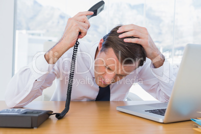 Annoyed businessman holding the telephone