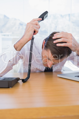 Irritated businessman holding the telephone