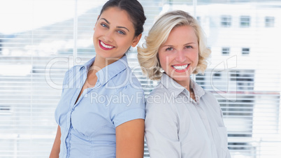 Attractive businesswomen standing back to back