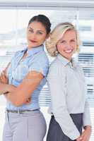 Attractive businesswomen with arms crossed standing back to back