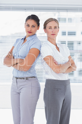 Serious businesswomen standing back to back